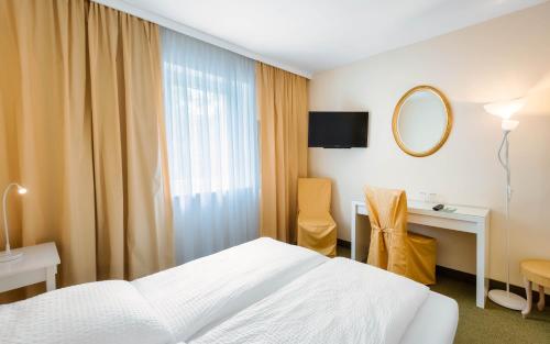 una camera d'albergo con letto e specchio di ALPHA HOTEL Hermann von Salza a Bad Langensalza
