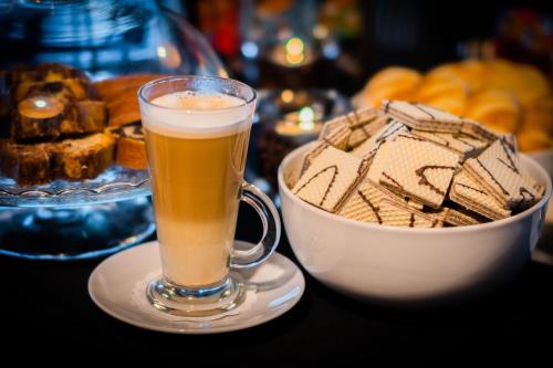 a cup of coffee next to a bowl of cookies at Hotel Lantier Wellness & Spa in Bytom