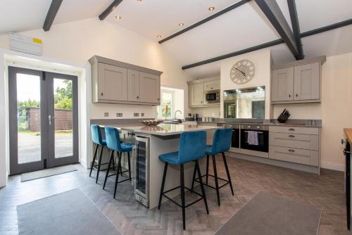 a kitchen with a large island with blue bar stools at East Farm Cottage in Durham