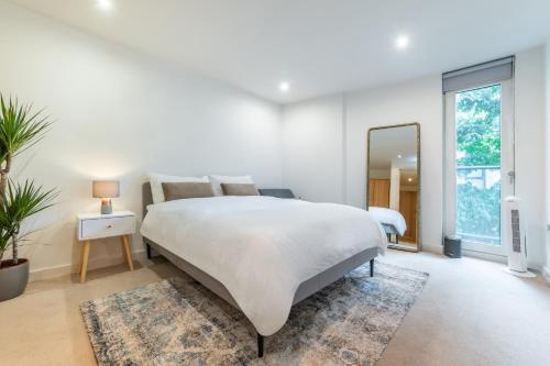 1 dormitorio blanco con 1 cama grande y espejo en Cosy apartment 15 minutes from Oxford Circus/Soho, en Londres