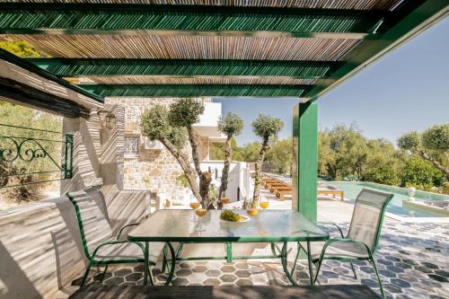 a patio with a table and chairs and a pool at Villa di Pietra in Lithakia