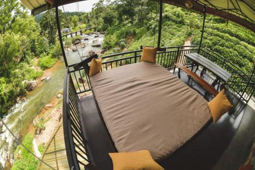 a hammock on a balcony overlooking a river at Dolagawa in Deniyaya