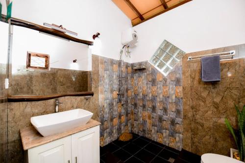 ein Bad mit einem Waschbecken und einer Dusche in der Unterkunft Dolagawa in Deniyaya
