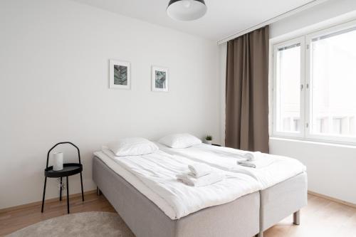 a white bedroom with a bed and a window at 2ndhomes Tampere "Posteljooni" Apt - New 1BR Apt with Balcony and Best Location in Tampere