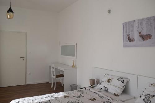 a white bedroom with a bed and a desk at Apartman Bambi in Vojnić