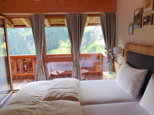 a bedroom with a white bed and large windows at Bichlhof in Kaisers