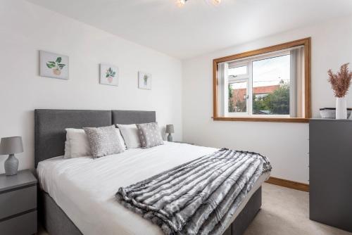 um quarto branco com uma cama grande e uma janela em West Sands - Donnini Apartments em Ayr