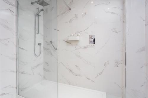a white bathroom with a shower with a glass door at West Sands - Donnini Apartments in Ayr