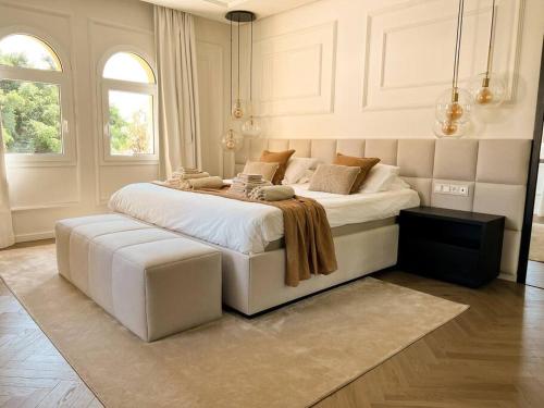 1 dormitorio blanco con 1 cama grande con reposapiés en Luxury pool villa at Malaga's best beach!, en Málaga