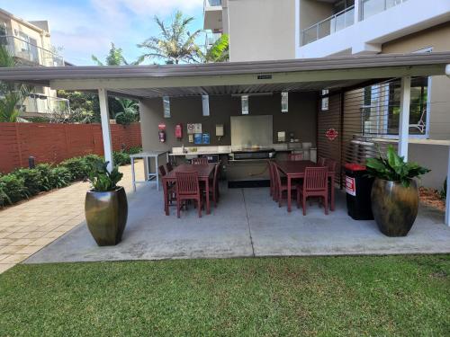 a patio with tables and chairs and a grill at 40 William Street Apartments in Port Macquarie