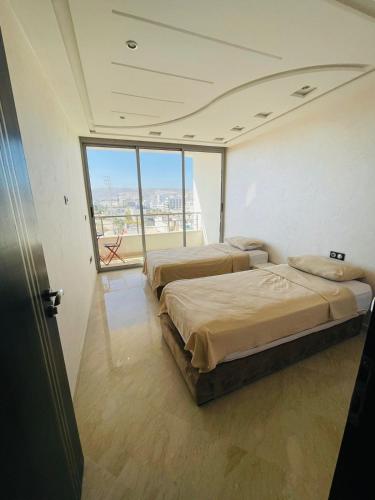 two beds in a room with a large window at Very nice apartment near the city center & beach in Agadir