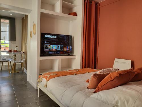 a bedroom with a bed with a flat screen tv on the wall at Appart' Terracotta - Champs Élysées 20 mn - JO 2024 in Maisons-Laffitte