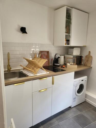 a kitchen with white cabinets and a sink and a washing machine at Appart' Terracotta - Champs Élysées 20 mn - JO 2024 in Maisons-Laffitte