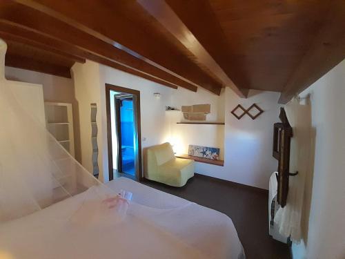 1 dormitorio con 1 cama blanca y 1 silla en Rustico San Leonardo, en Cinisi