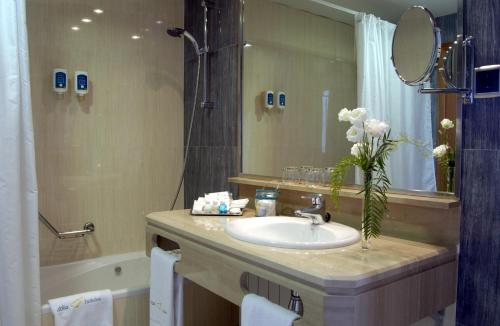 La salle de bains est pourvue d'un lavabo et d'un grand miroir. dans l'établissement Abba Garden, à Barcelone