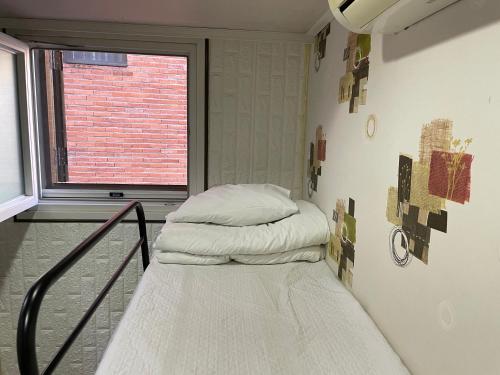 uma cama num quarto com uma janela em Chloe Hostel em Seul