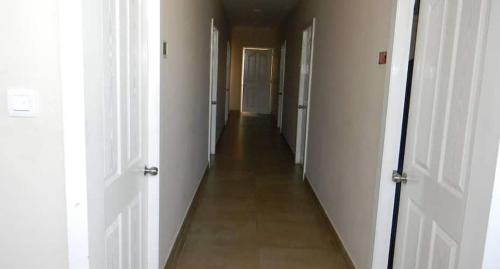 a hallway with two white doors and a long corridor at Hotel Mothimahal in Trichūr