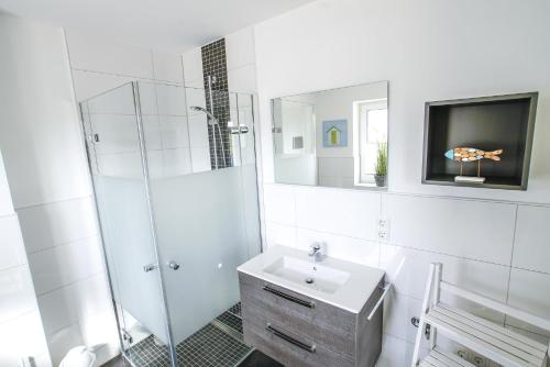 a white bathroom with a sink and a shower at Ferienhaus 16 "Gut Tossens" in Tossenserdeich