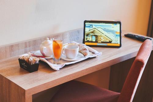 a table with a tablet and a breakfast of coffee and orange juice at Hotel Mondolé - Azzurro Club in Prato Nevoso
