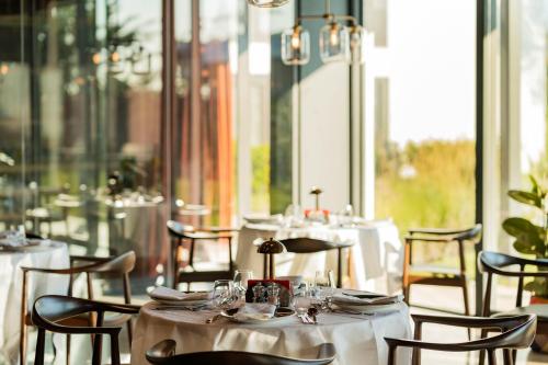 een restaurant met witte tafels, stoelen en ramen bij Pınar Otel in Erdek