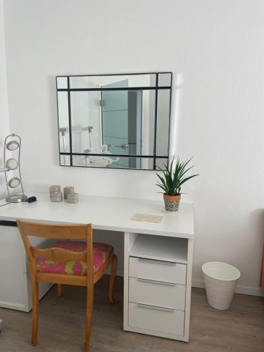 escritorio blanco con espejo y silla en Doppelzimmer en Borgholzhausen
