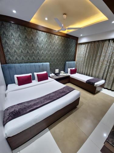 a bedroom with two beds with red pillows at Hotel City Heart Shirdi in Shirdi