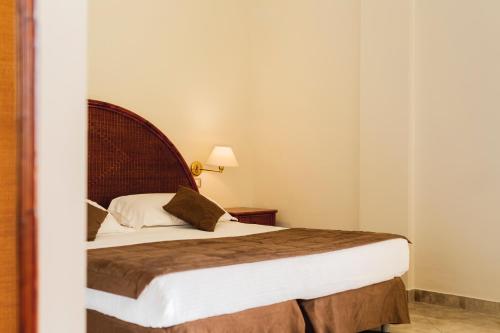 a bedroom with a bed with a wooden headboard at Apulia Hotel Taranto Ara Solis in Lido Azzurro