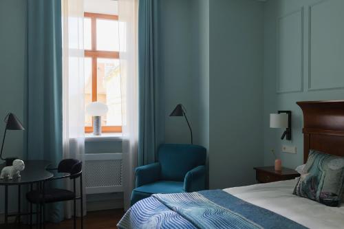 a bedroom with a bed and a blue chair and a window at Leopolis Hotel in Lviv