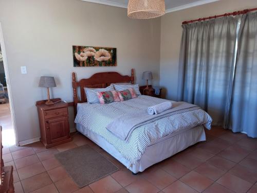 UtrechtLuiperdkloof Trout Lodge的一间卧室配有一张床和床头柜,配有四柱床和四柱床。