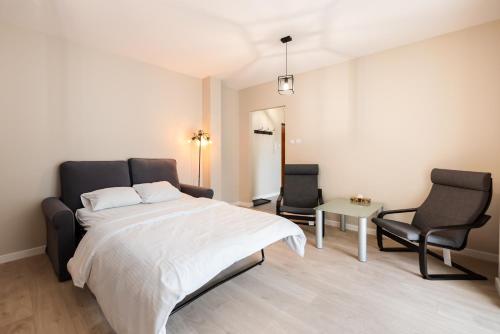 a bedroom with a large bed and two chairs at Ursus Pleasant Apartment in Warsaw