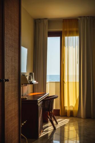 a hotel room with a desk and a window at Apulia Hotel Taranto Ara Solis in Lido Azzurro