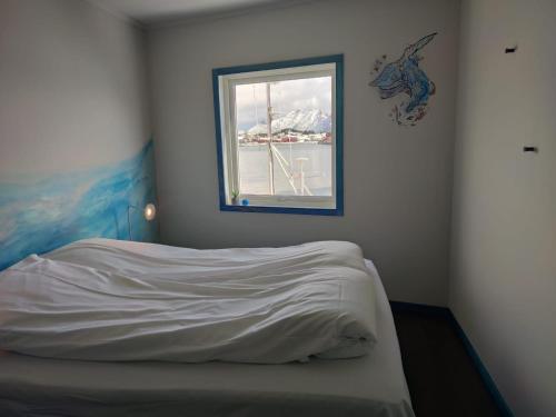 a bedroom with a bed with a window in it at Fish factory -The real Lofoten experience in Ballstad