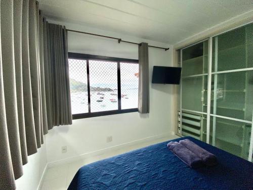 Un dormitorio con una cama azul y una ventana. en Angra dos Reis Apartamento com Vista para o Mar 6 Condomínio Porto Bali Complexo Mercure, en Angra dos Reis