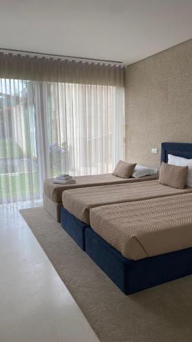 a bedroom with two beds and a large window at FH Hotel Rural in Felgueiras