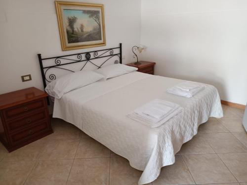 ein Schlafzimmer mit einem weißen Bett und einem Bild an der Wand in der Unterkunft Acqua Cristallina in Arenella