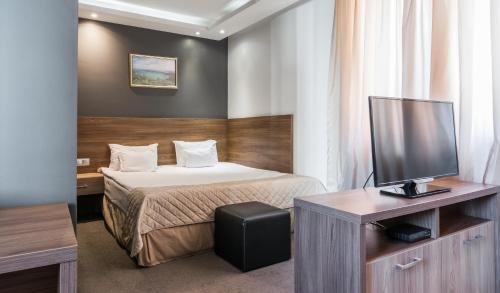 ソフィアにあるHotel Calipso Hotelのベッド1台、薄型テレビが備わるホテルルームです。