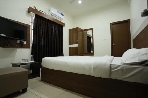 a hotel room with a bed and a television at Hotel Sigma Suites in Bengaluru