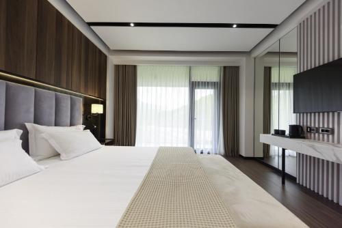 a bedroom with a large white bed and a desk at Hotel Uji Ftohte Tepelene in Tepelenë