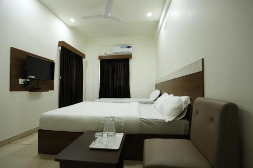 a hotel room with a bed and a table and a couch at Hotel Sigma Suites in Bangalore