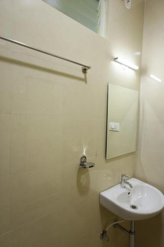 a white bathroom with a sink and a mirror at Hotel Sigma Suites in Bengaluru