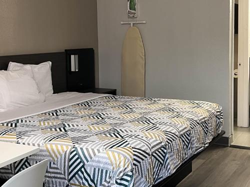 a bedroom with a bed with a black and white comforter at Studio 6 Bay Minette AL in Bay Minette