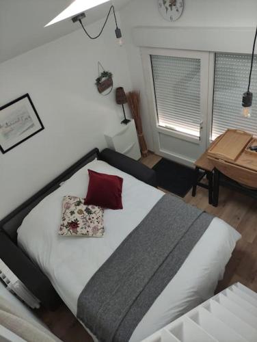 - une chambre avec un grand lit blanc et un oreiller rouge dans l'établissement Studio tout confort à 10mn de Royan et plages, à Saint-Sulpice-de-Royan
