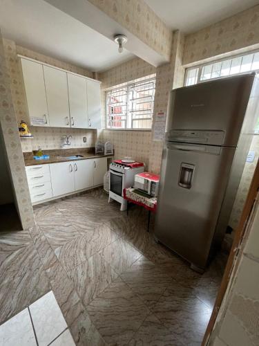 a kitchen with a stainless steel refrigerator and white cabinets at Pousada Regina in Cachoeiro de Itapemirim