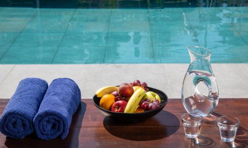 a bowl of fruit and towels on a table next to a swimming pool at Rodostamo Hotel & Spa- Adults Friendly in Kommeno