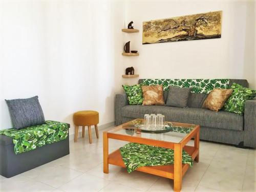 a living room with a couch and a table and a chair at Bougainvillea Home - Ospedale Policlinico Monserrato in Monserrato