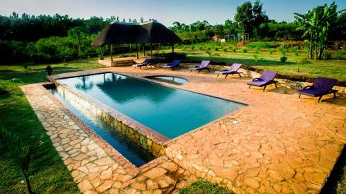 a swimming pool with purple chairs and a umbrella at Buyala Bliss on the Nile in Jinja