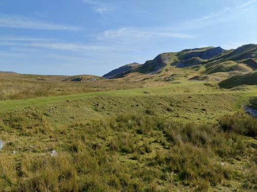 a field of grass with mountains in the background at Pentre Riding Stables in Abercraf