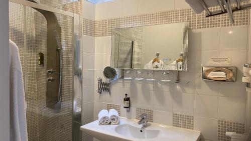 a bathroom with a sink and a shower with a mirror at Hotel Bellevue in Amboise