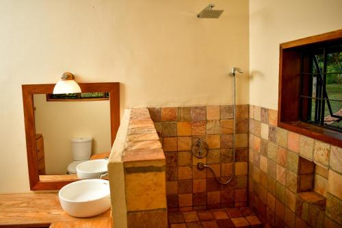 a bathroom with two sinks and a shower with a mirror at Buyala Bliss on the Nile in Jinja