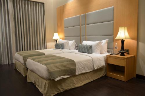 a hotel room with two beds and two lamps at The Umrao in New Delhi